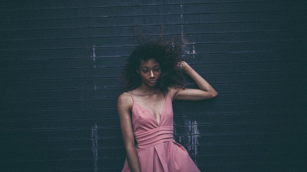 Here you can see that the black wall absorbs light rather than reflects it. The woman has this great slash of light on her nose, but overall the image is muted. | photo from unsplash